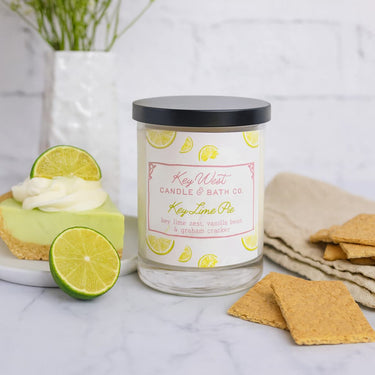 Key Lime Pie candle from Key West Candle & Bath Co. with a slice of key lime pie and graham crackers on a marble surface.