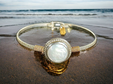 Gold bracelet with a large stone on a wet beach