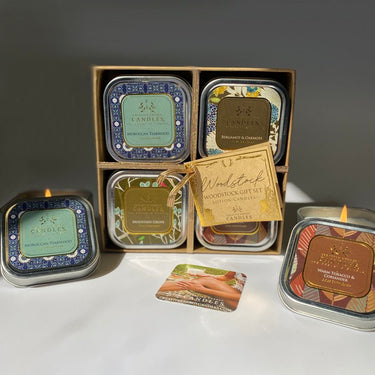 Set of small Soy Candles in tin containers with decorative labels on a white surface.