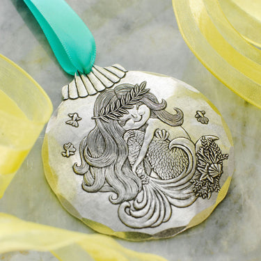 Mermaid medallion with a green ribbon on a marble surface