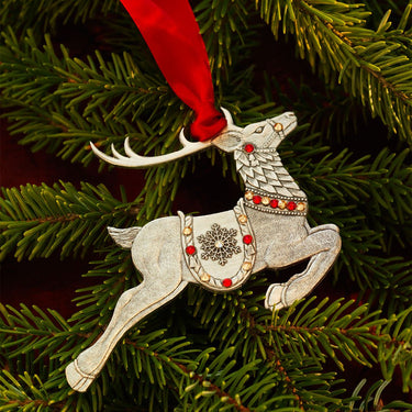 Decorative reindeer ornament with red ribbon on a Christmas tree.