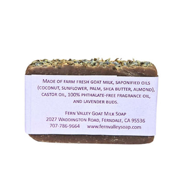 Bar of Moisturizing Goat Milk Soap - Lavender and Black Amber
 with a label detailing ingredients and contact information on a white background