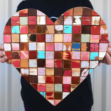 Heart-shaped mosaic made of colorful wooden squares held by a person.