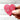 Hand holding a pink heart-shaped object with floral patterns on a white background