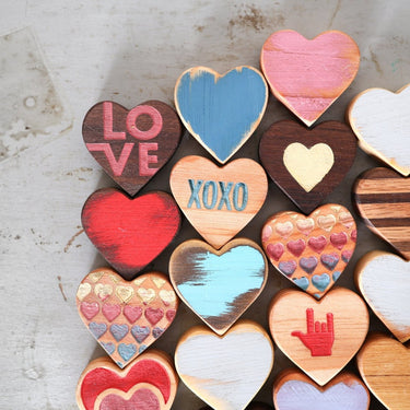 Collection of colorful heart-shaped wooden decorations on a textured surface