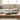 Beige sofa with a wooden coffee table featuring a Coral Beach Sculpture, books, and a plant.