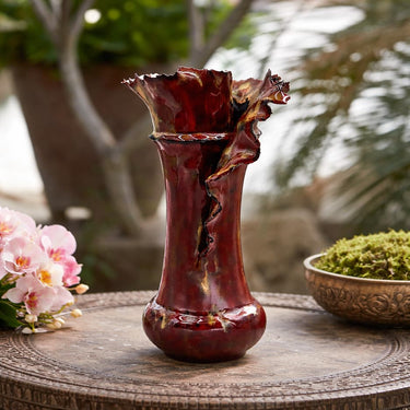 Decorative Brown Handcrafted Porcelain Vase on a wooden table with blurred greenery in the background