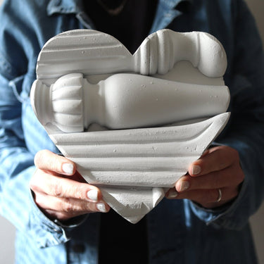 Heart-shaped sculpture of a couple embracing held by a person