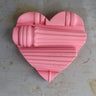 Pink heart-shaped object on a textured surface