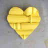 Yellow heart-shaped object on a textured surface