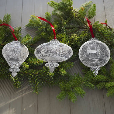 Decorative silver Christmas ornaments on a green branch against a wooden background
