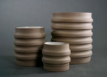 Three Beige Modern ceramic planter for indoor or outdoor plants with ribbed design on a gray background