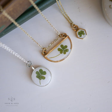 Two necklaces with clover pendants on a white surface