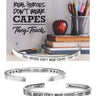Silver bracelet with motivational quote on a desk with books and an apple