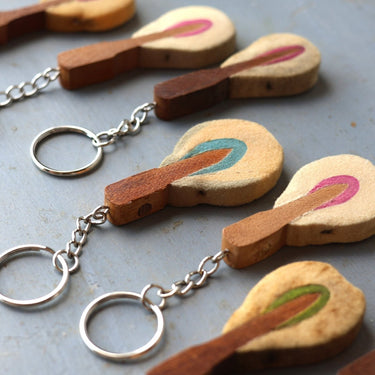 Wooden guitar-shaped keychains on a metal surface