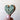 Heart-shaped object with wavy pattern held by a hand against a plain background