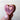 Wooden heart-shaped object with a carved design held by a hand against a light background