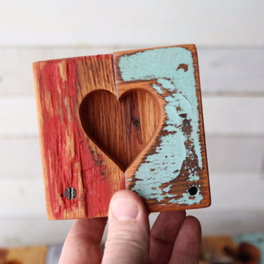 Wooden heart-shaped object held by a hand against a white background