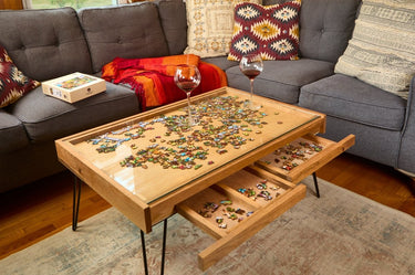 Wooden coffee table with puzzle pieces and drawers, placed on a gray sofa.