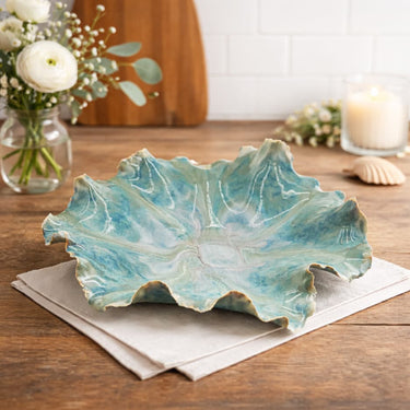 Sea Glass Beach Bowl on a wooden table with flowers and a candle in the background.