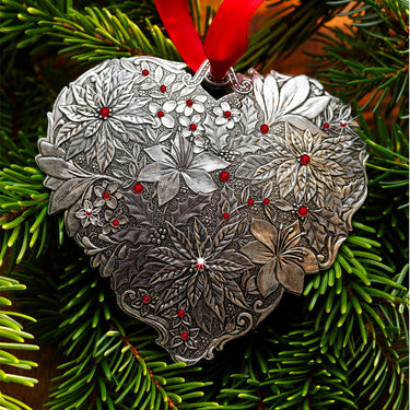 Decorative heart-shaped ornament with floral patterns on a green pine branch.