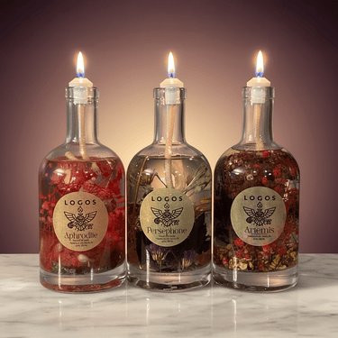 Three lit oil lamps made from glass bottles with visible labels on a marble surface.