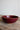 Red ceramic bowl on a wooden surface with a plain background