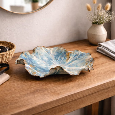 Shorebreak Blossom Bowl shell bowl on a wooden surface with a vase and mirror in the background