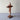 Wooden cross sculpture on a light gray surface with a white textured wall background