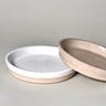 Two ceramic bowls, one white and one beige, on a gray background