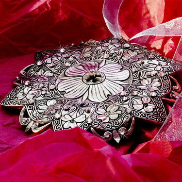 Decorative silver plate with floral patterns on a red fabric background
