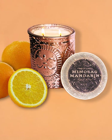 Candle in a rose gold  jar with oranges and a label on an orange background