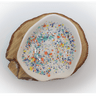Ceramic dish with colorful speckles on a wooden base