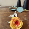 Colorful porcelain rose on a wooden surface with black vases in the background