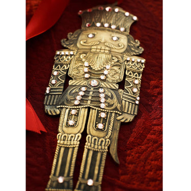 Decorative brooch shaped like a nutcracker on a red fabric background