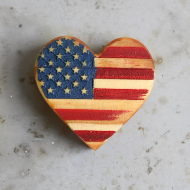 Heart-shaped object with American flag design on a textured surface
