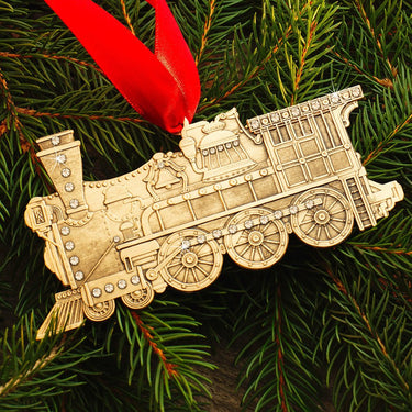 Gold train ornament on a green pine branch with a red ribbon